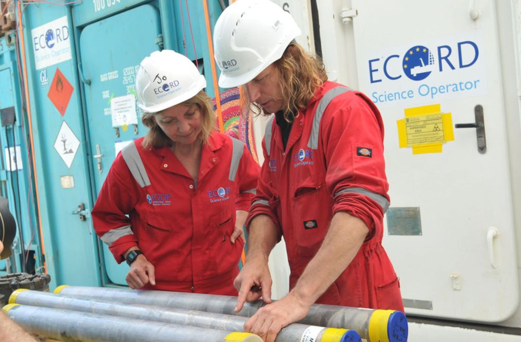 Sean Gulick (rechts) mit Joanna Morgan, Professorin am Imperial College London, stehen während der Forschungsexpedition des International Ocean Discovery Program, an Bohrkernen aus dem versunkenen und vergrabenen Einschlagkrater.