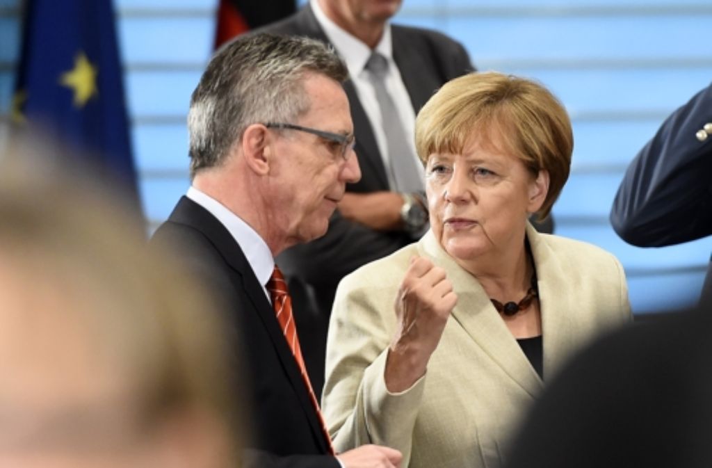 Innenminister Thomas de Maizière bespricht sich mit Angela Merkel im Bundestag. In seiner Rede versuchte er, die Flüchtlingskrise menschlich zu sehen. Foto: AFP