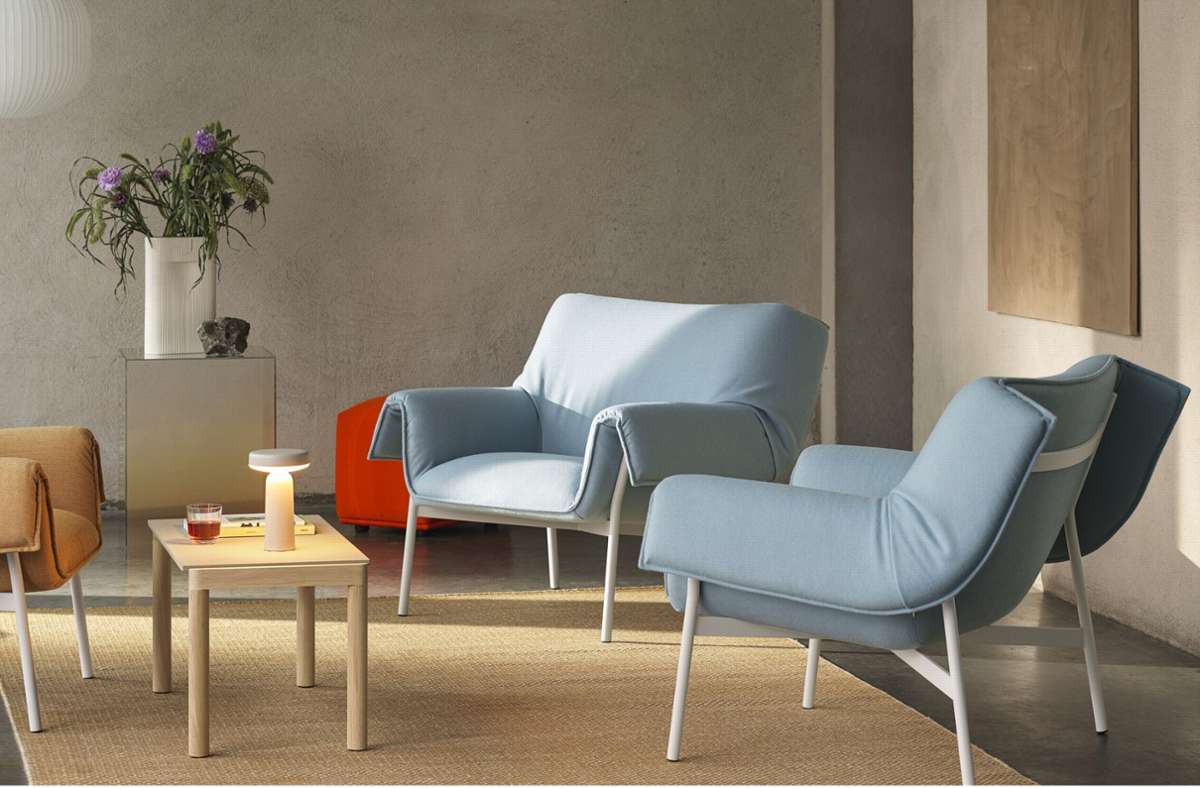 Sessel mit überlappendem Bezug von Muuto: „Wrap Lounge Chair“ in gräulichem und sandfarbenen Versionen, ein kleiner Couple Coffee Table Tisch aus Eiche und ein terrakottafarbener Teppich namens „Ply“.