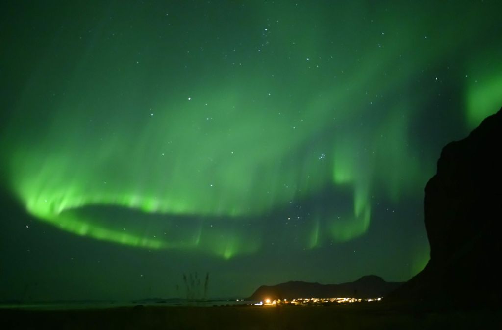 Grüne Nordlichter über dem norwegischen Ort Unstad auf den Lofoten.