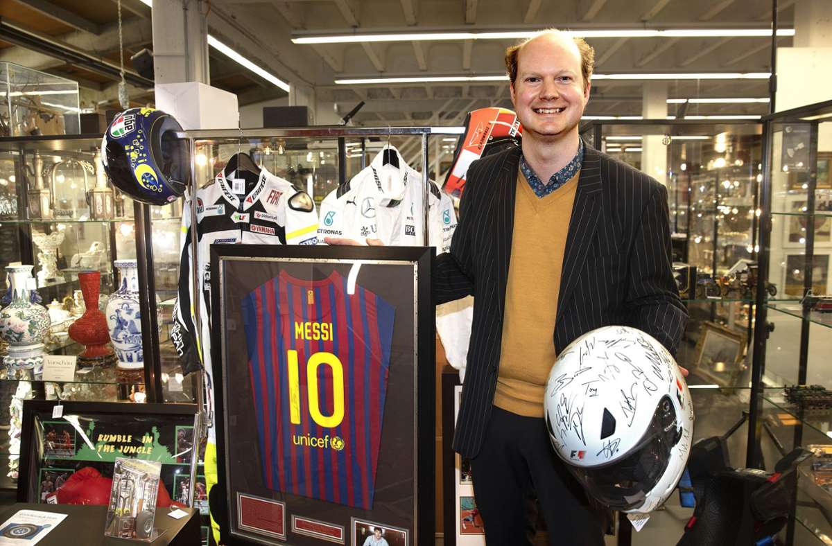 Sebastian Pumpmeier von Eppli zeigt ein  Messi-Trikot und den Helm von Michael Schumacher – beide Stücke waren Teil der Auktion. Foto: Horst Rudel/Rudel