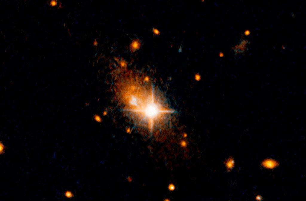 Der helle, sternenähnliche Quasar (Bildmitte), der der aktive Kern einer Galaxie ist, ist vor seiner Heimatgalaxie zu sehen. Ein gigantischer Gravitationswellen-Tsunami schleudert, wie auf dem undatierten Foto zu sehen ist, in supermassereiches Schwarzes Loch aus dem Herz seiner Heimatgalaxie.