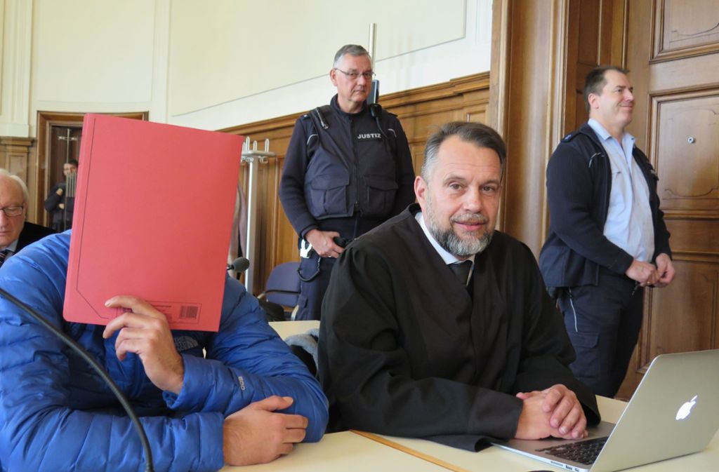 Einer der Angeklagten verdeckt sein Gesicht im Prozess. Foto: dpa/Miriam Steinruecken