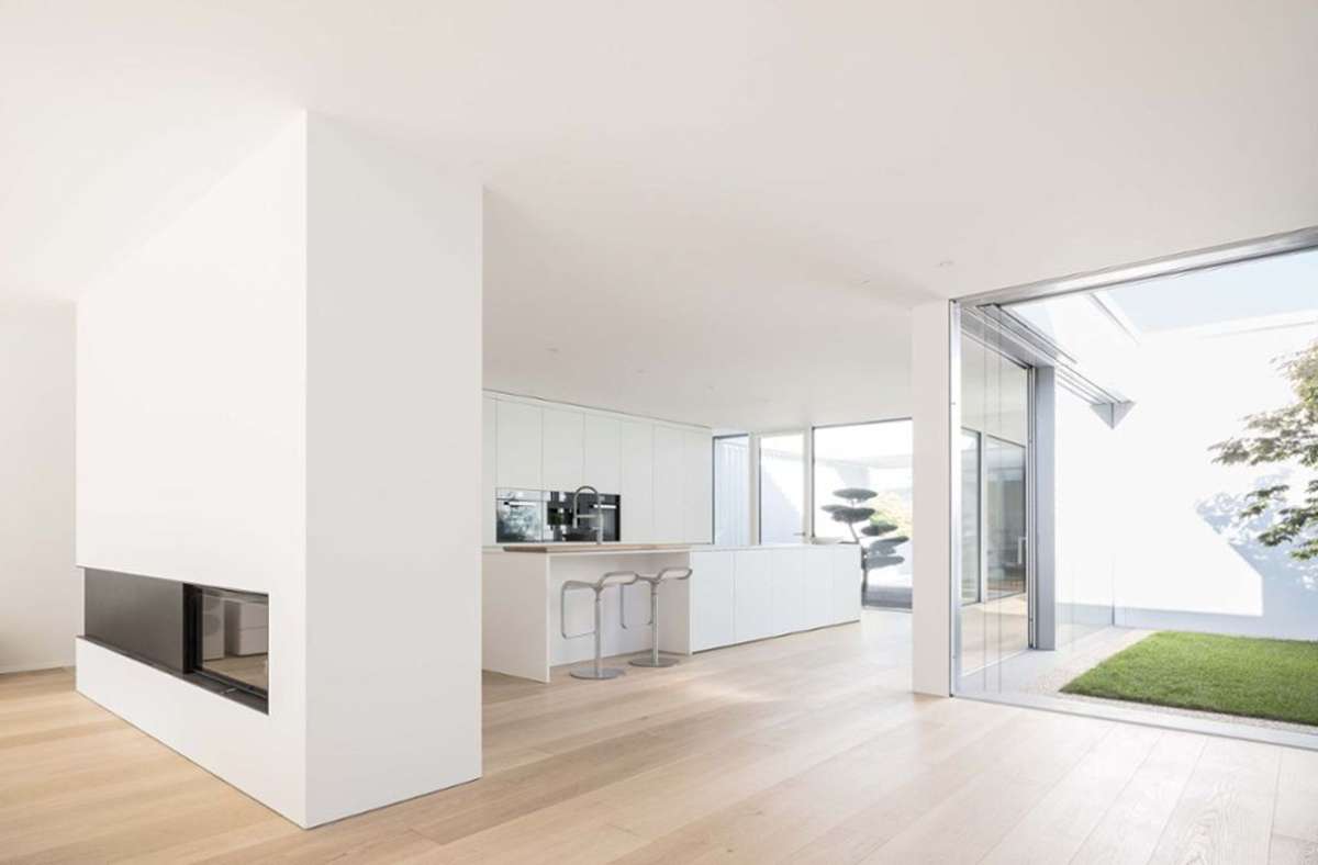 Blick in die Küche und auf den Kamin, der als Raumteiler zwischen Wohnzimmer und Essküche fungiert, entworfen wurde der Bungalow von dem Architekten Bernd Liebel.