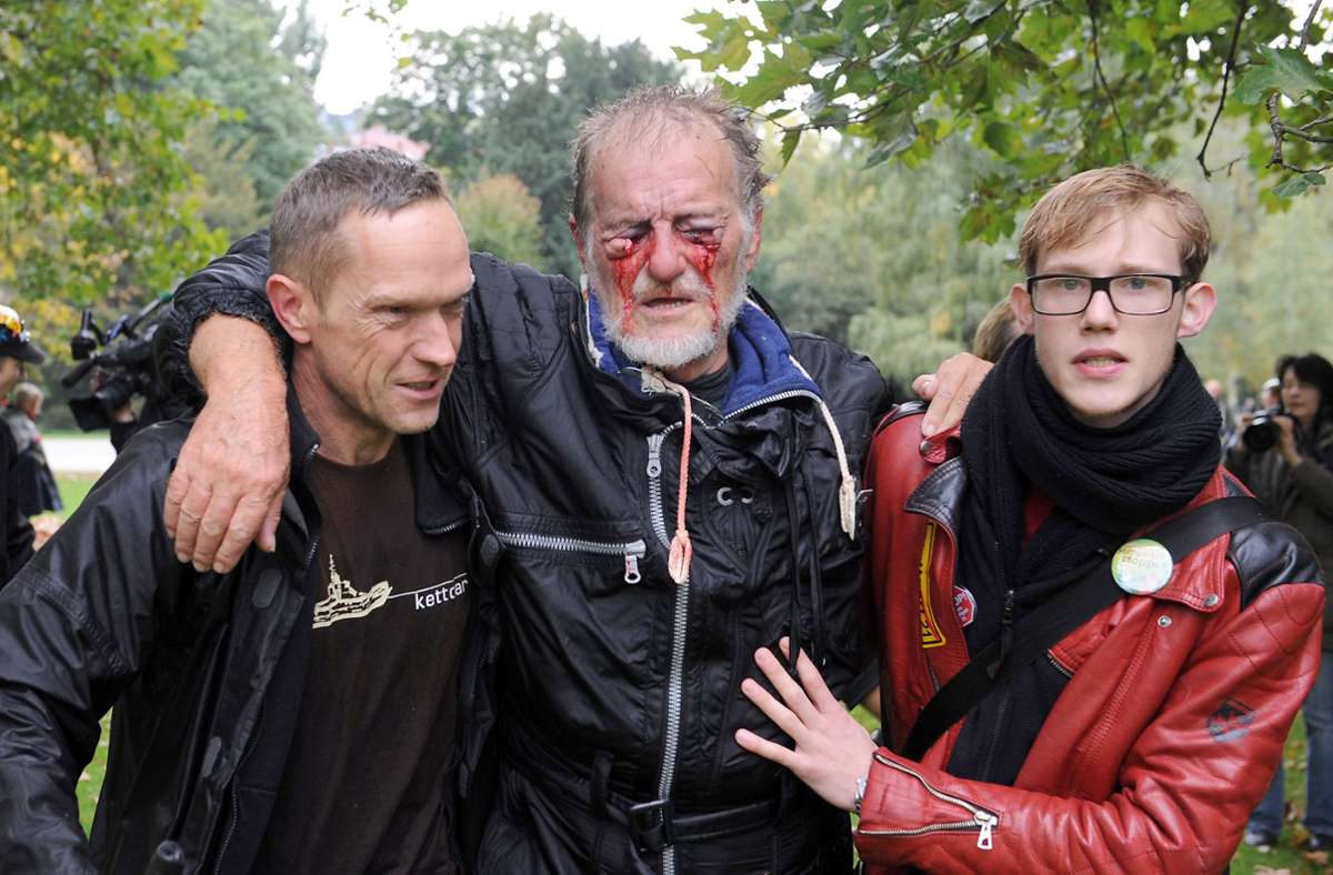 Zwei Männer stützen den verletzten Dietrich Wagner, der im Nachgang zu einer Ikone der Folgen des harten Polizeieinsatzes wird: Er ist heute weitgehend erblindet.
