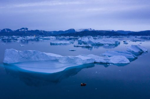 Ein kleines Boot schwimmt inmitten eines Eisbergfeldes bei Kulusuk. Grönland ist besonders vom Klimawandel betroffen. Foto: /Felipe Dana/dpa