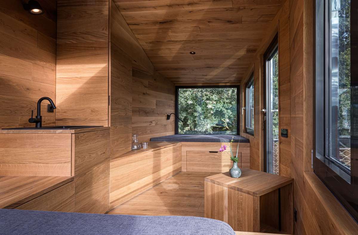 In dem zu beiden Seiten konisch geformten Innenraum befinden sich eine große Bettfläche, schräg geschnittene Einbaumöbel, ein Handwaschbecken und ein Sofabereich.