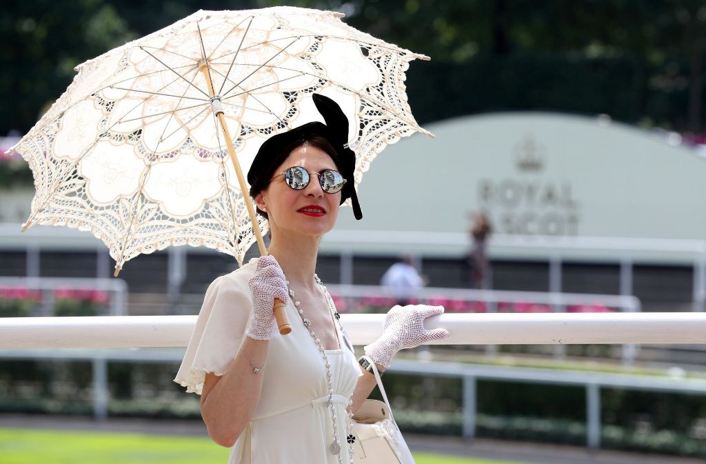 Diese Besucherin möchte gleich doppelt auffallen: Sie kombiniert ihre schwarze Kopfbedeckung mit einem weißen Sonnenschirm.