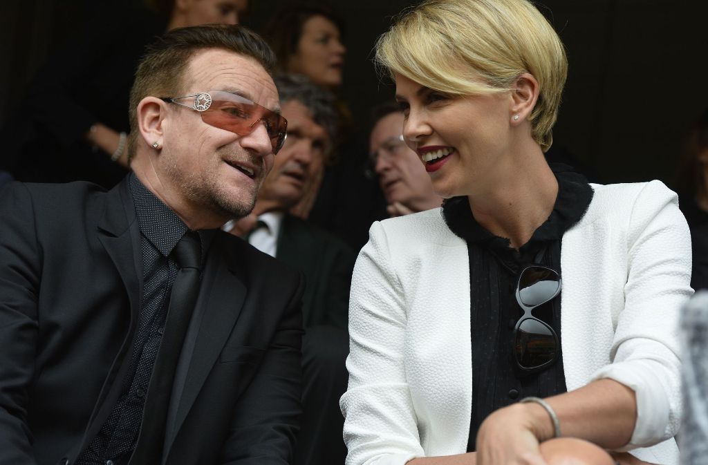 Bei der Trauerfeier für den verstorbenen ehemaligen südafrikanischen Präsidenten Nelson Mandela 2013 unterhält sich Charlize Theron mit Bono, dem Sänger der irischen Band U 2.