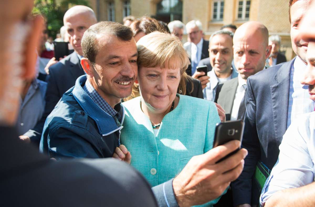 September 2015: Die Szene an sich ist wohl noch kein schwieriger Moment für Angela Merkel. Doch sie hat Folgen für die Kanzlerin. Entstanden ist dieses Selfie mit einem geflüchteten Mann beim Besuch einer Erstaufnahmeeinrichtung für Asylbewerber in Berlin-Spandau. Das Bild ging – ebenso wie einige ähnliche – um die Welt. In Deutschland aber wurde es insbesondere von Gegnern der Flüchtlingspolitik von Merkel geteilt. Trotz des Gegenwindes macht Merkel deutlich, dass sie bei ihrer Linie bleibt: „Wenn wir jetzt anfangen, uns noch entschuldigen zu müssen, dass wir in Notsituationen ein freundliches Gesicht zeigen, dann ist das nicht mein Land“, sagt sie.