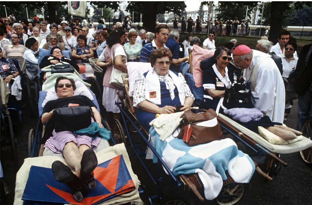 Ein Geistlicher spricht während des Besuches von Papst Johannes Paul II. im Jahr 1983 vor der Grotte von Lourdes mit Kranken und Behinderten.
