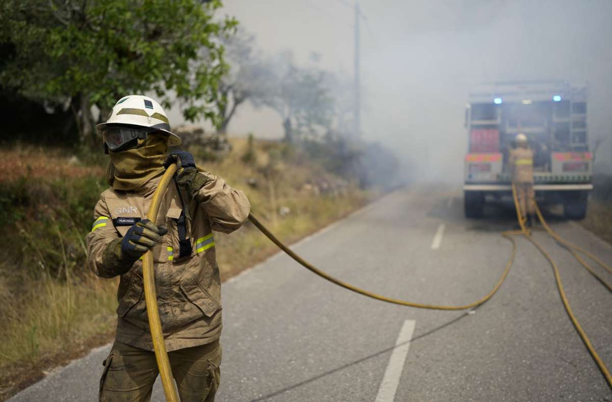 Ein Feuerwehrmann zieht einen Schlauch, während er einen Waldbrand in dem Dorf Rebolo in der Nähe von Ansiao löscht.