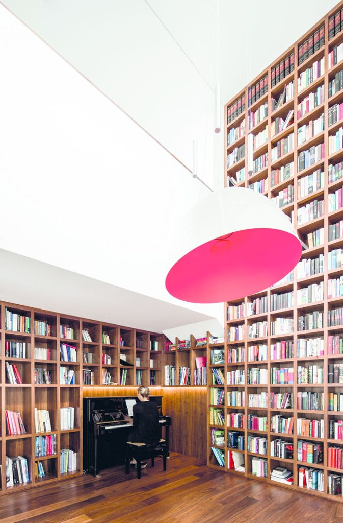 Die beeindruckende Bibliothek befindet verbindet Haupt- und Obergeschoss, ein Klavier findet in dem Raum auch noch Platz. Der sechs Meter hohe Luftraum befindet sich im Drehpunkt des Gebäudes, er bringt Licht und Luftigkeit ins Haus.