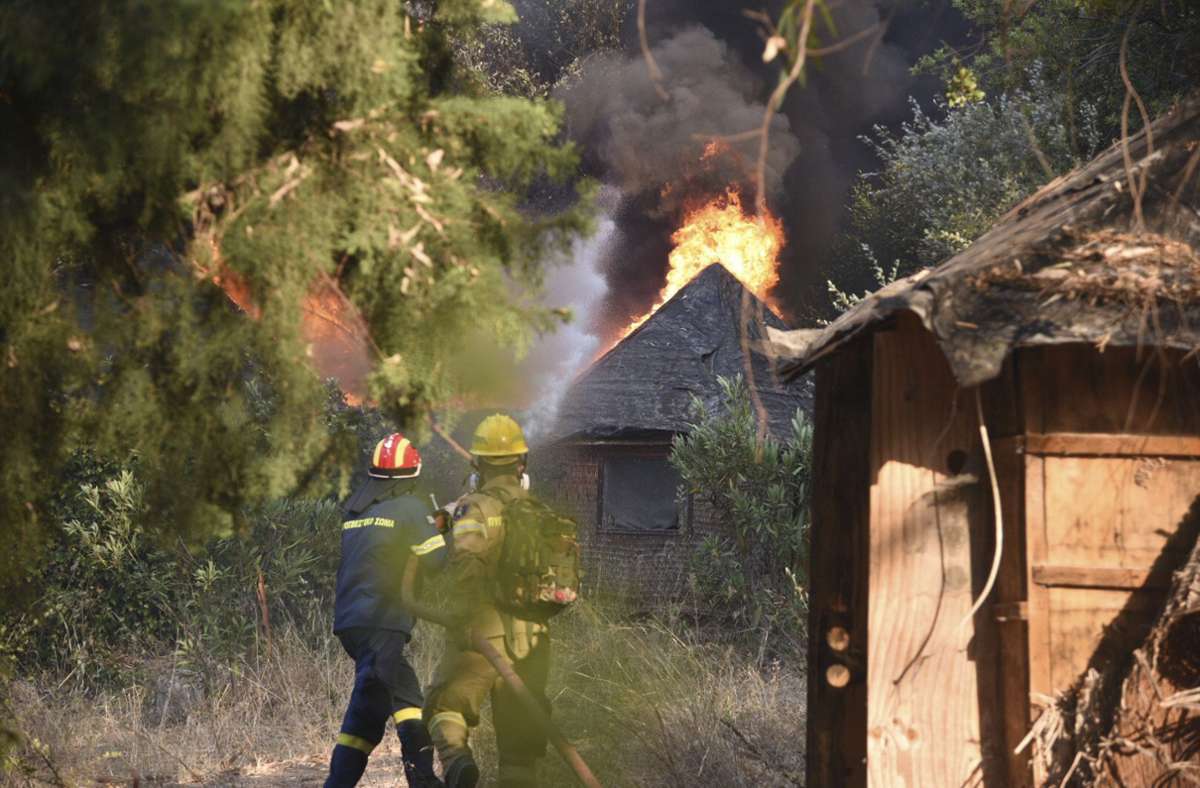 Feuerwehrleute bekämpfen einen Waldbrand in der Nähe des Dorfes Lampiri.