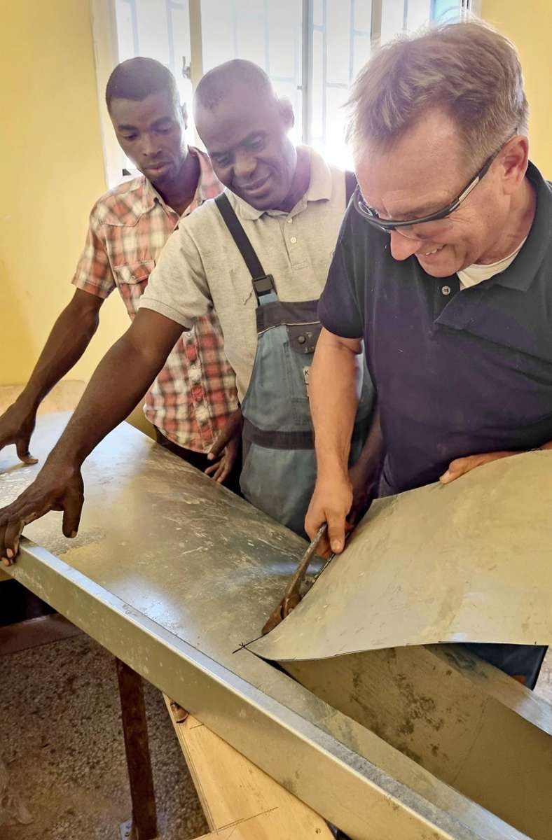 Rolf Exler zeigt Schülern aus Tansania, wie man Blech bearbeiten und ein Waschbecken für die Küche fertigen kann.