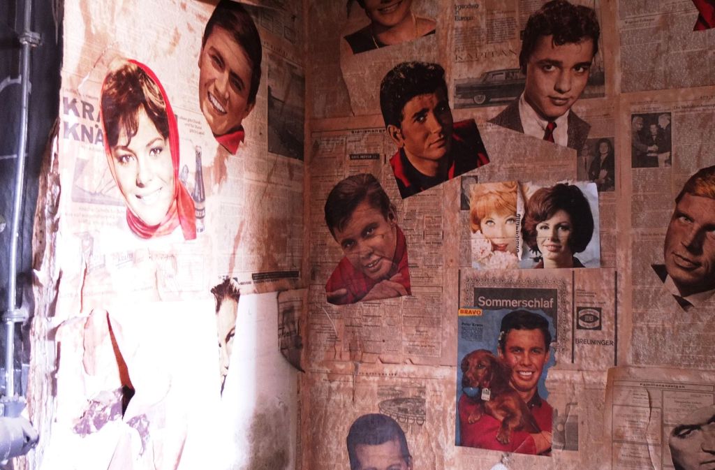 Die Wände sind mit Zeitungsseiten und alten Postern aus den Fünfzigerjahren beklebt. Toiletten ...