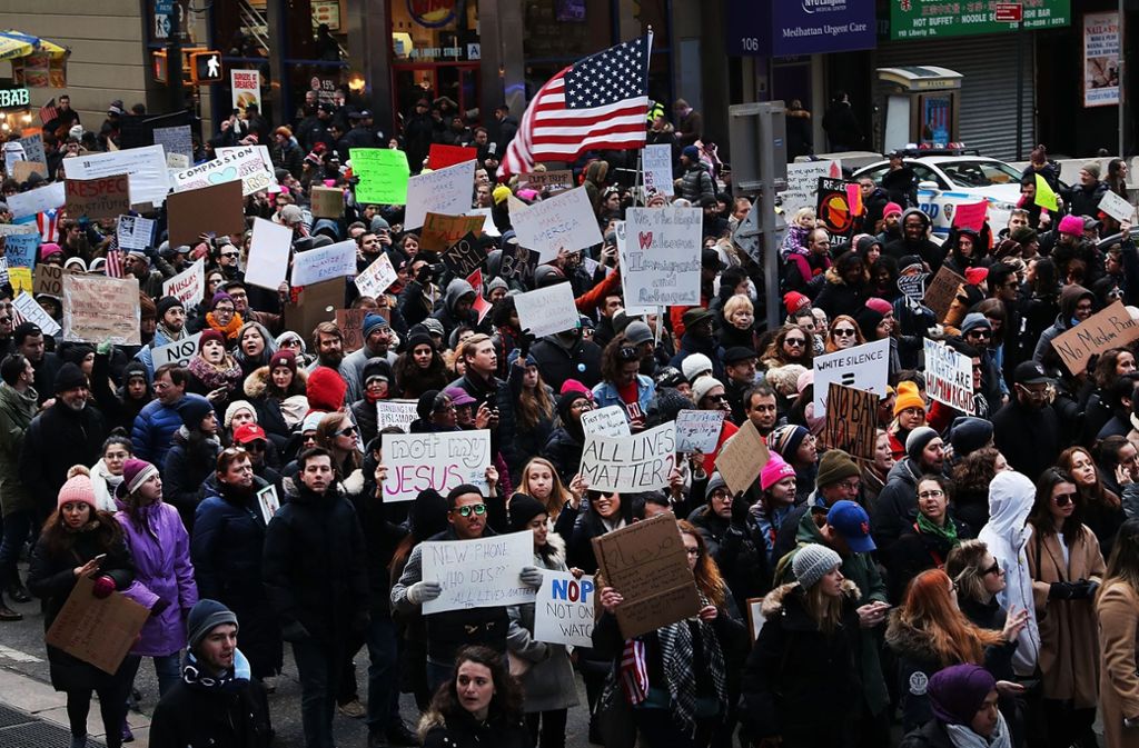 Hunderte Menschen halten bei einem Protestmarsch in New York selbstgemalte Schilder in die Höhe.