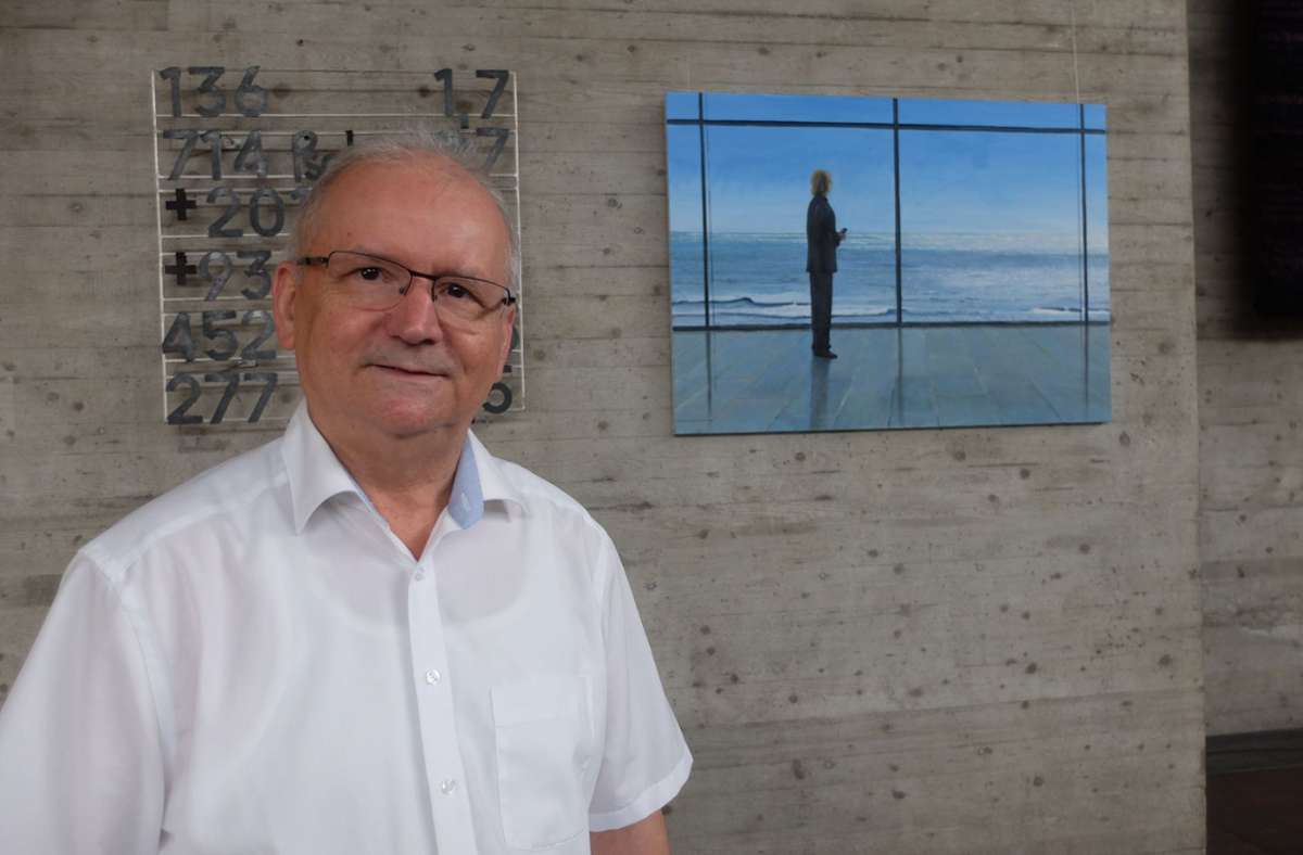 Pfarrer Andreas Jauss vor seinem Gemälde, auf dem ein Mensch am Meer steht, abgetrennt von einer Glaswand.