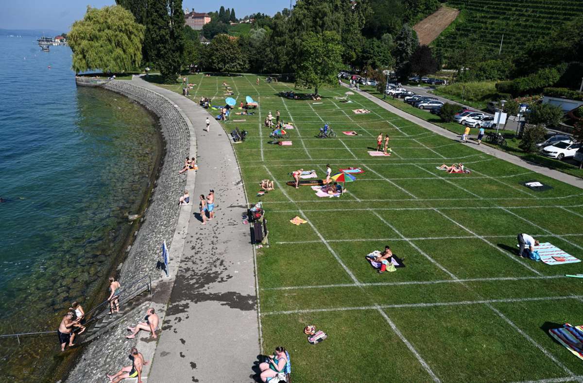 In Meersburg liegen Sonnenbadende an der Uferpromenade, die die Stadt mit einem Fußballfeld-Streuwagen in Einzelabschnitte aufgeteilt hat.