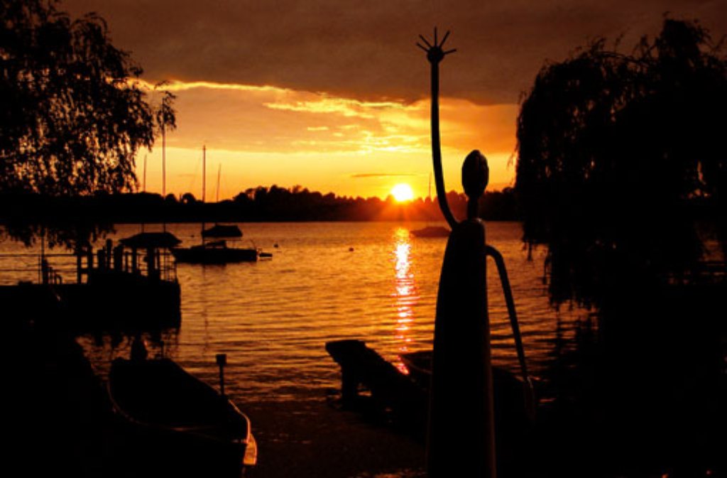 Am Abend auf der Fraueninsel: Sonnenuntergang über Herrenchiemsee, gesehen von der Fraueninsel aus. Im Vordergrund eine Skulptur des Bildhauers Heinrich Kirchner.