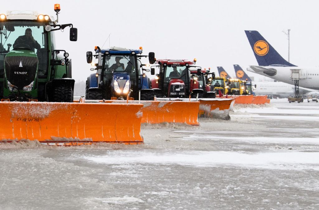Traktoren mit Schneeschaufeln befreien am Terminal 2 am Flughafen München das Vorfeld von Schnee.