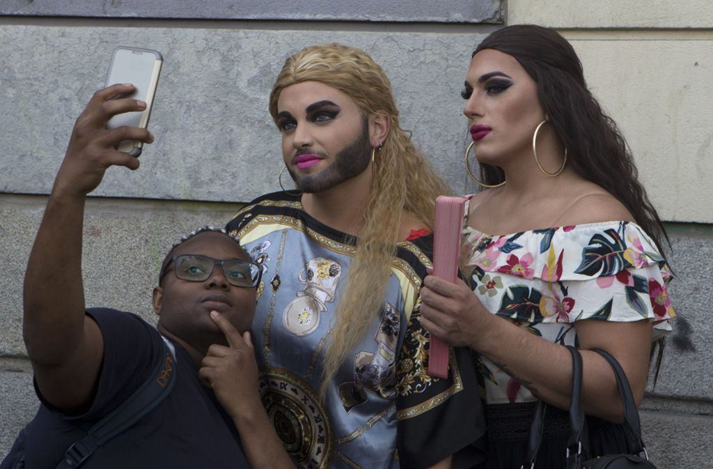 Eine Frau macht ein Selfie mit zwei Feiernden bei der Eröffnung der World Pride im zentral gelegenen Stadtviertel Chueca in Madrid.