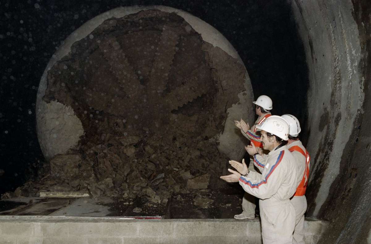 Französische Arbeiter applaudieren einer Tunnelbohrmaschine.