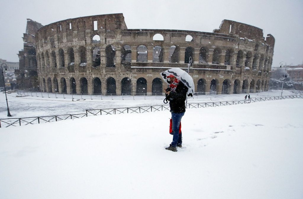 Ein Mann steht vor dem Kolosseum im Schnee. Ein Kältetief mit Schnee, Regen und starkem Wind hat Italien erreicht.