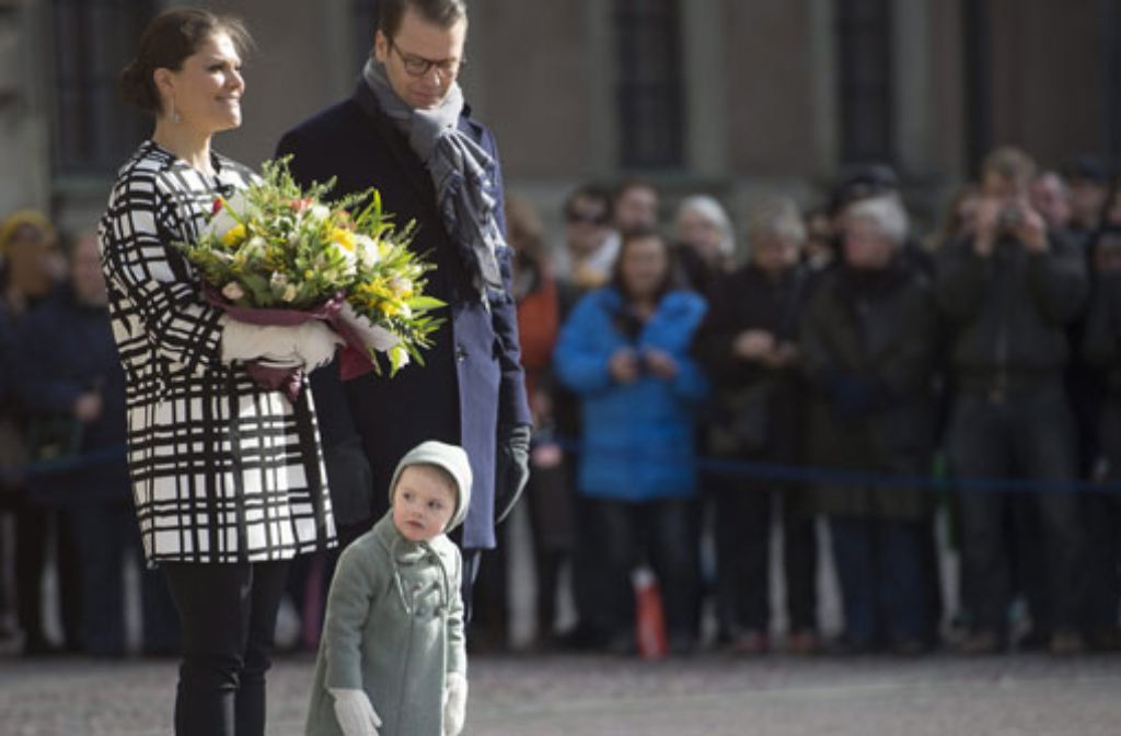 Neugierig linst die kleine Prinzessin Estelle an den Beinen ihrer Eltern Victoria und Daniel von Schweden vorbei.