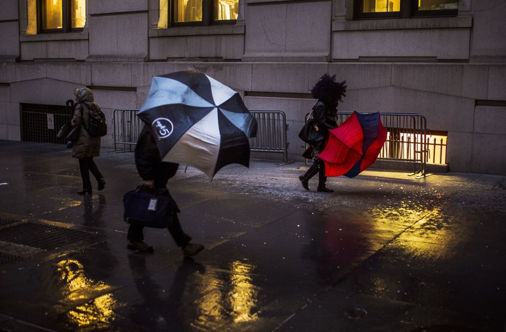 Passanten kämpfen am in New York (USA) gegen den starken Wind an.