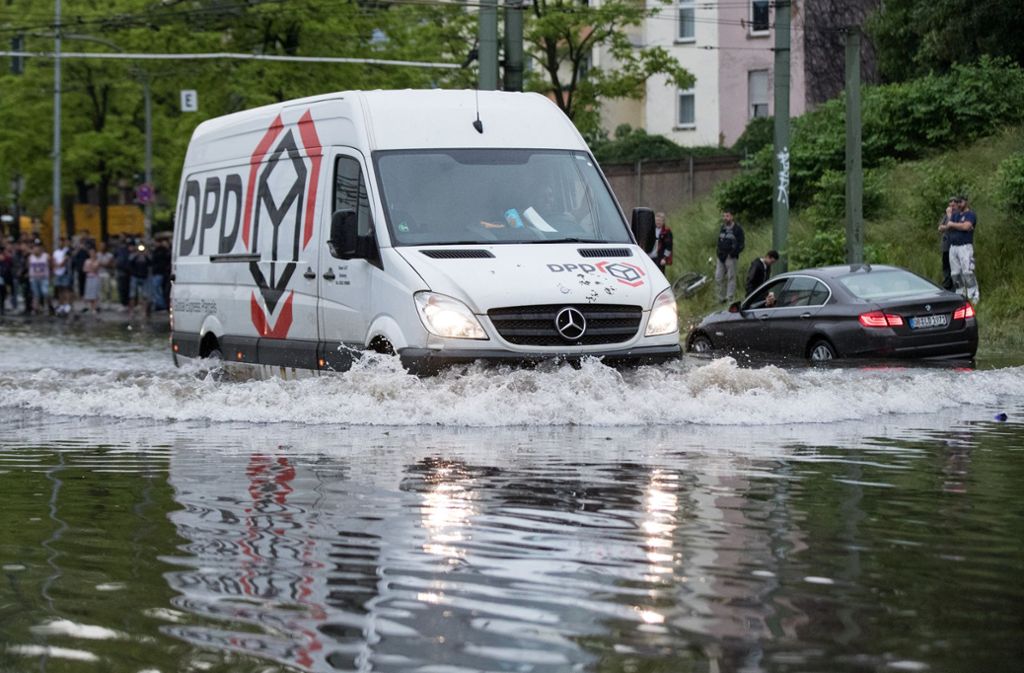 In Duisburg fährt ein Lieferwagen über eine überflutete Straße.