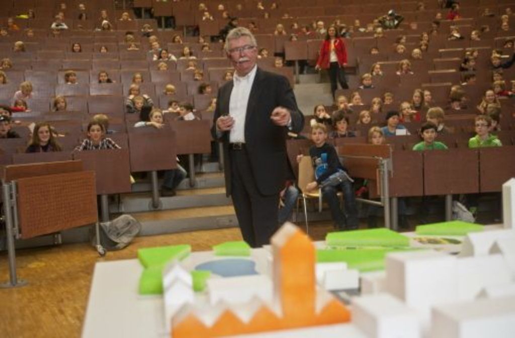 Der Kinder-Uni-Professor Franz Pesch hat eine riesige Modellstadt im Hörsaal aufbauen lassen. Die kleinen Zuhörer durften sich aussuchen, welche Gebäude hier wichtig sind: zum Beispiel grüne Parkflächen oder eine orangefarbene Feuerwehr.