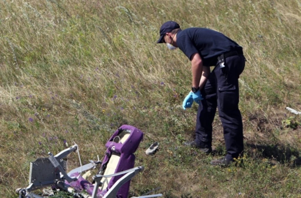niederländische Experten untersuchen am MH17-Absturzort Wrackteil. - Stuttgarter Zeitung
