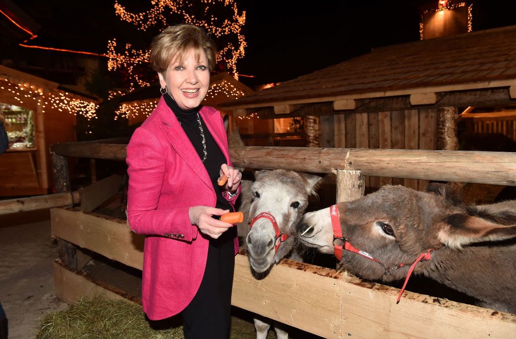 Moderatorin Carolin Reiber im magentafarbenen Blazer bei der Fütterung der Esel