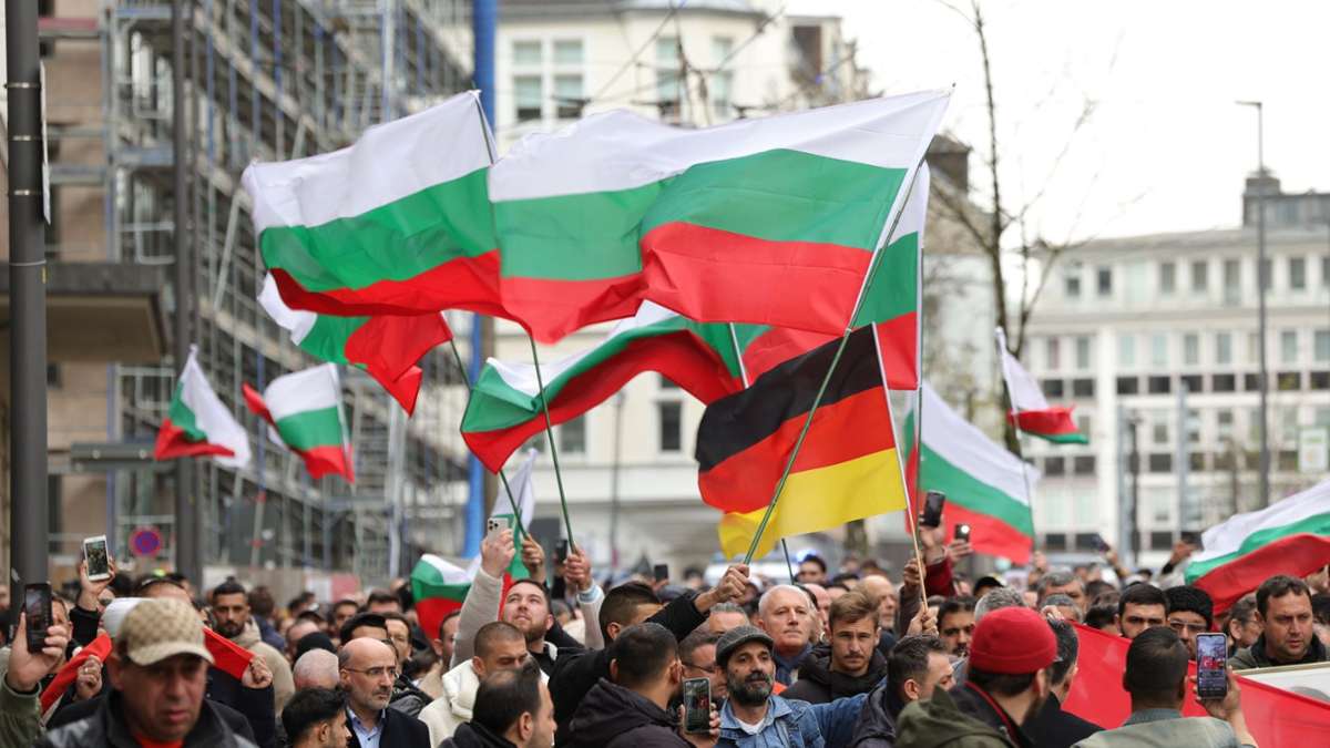 Mit bulgarischen und deutschen Flaggen ziehen Teilnehmer von der Solinger Innnenstadt zu dem ausgebrannten Haus, in dem eine aus Bulgarien stammende Familie bei einer mutmaßlichen Brandstiftung ums Leben kam.