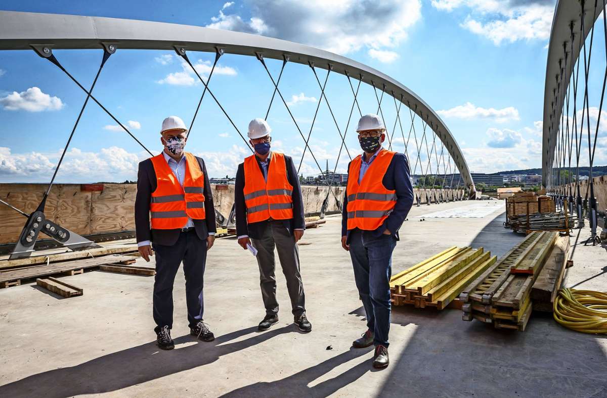 SSB-Chef Thomas Moser, Esslingens Landrat Heinz Eininger und Verkehrsminister Winfried Hermann (von links) vorschriftsmäßig maskiert auf der Stadtbahnbrücke über die A8