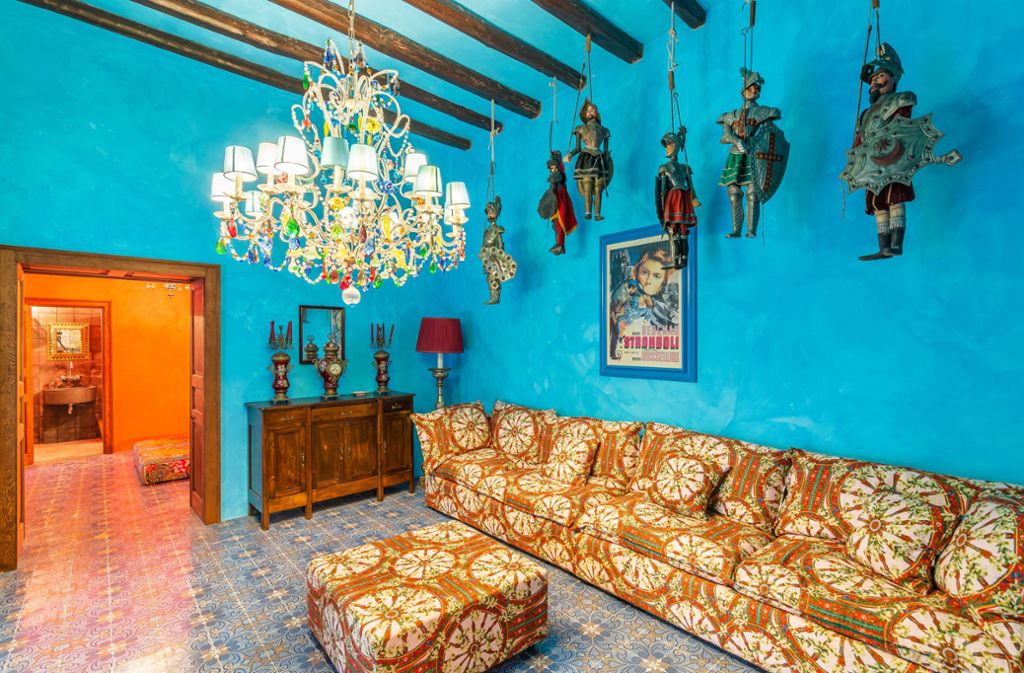 Innenansicht eines Wohnraums in der Villa des Designerduos Dolce und Gabbana auf der Vulkaninsel Stromboli. Marionetten in Rüstungen hängen von der türkisblau getünchten Decke herab.