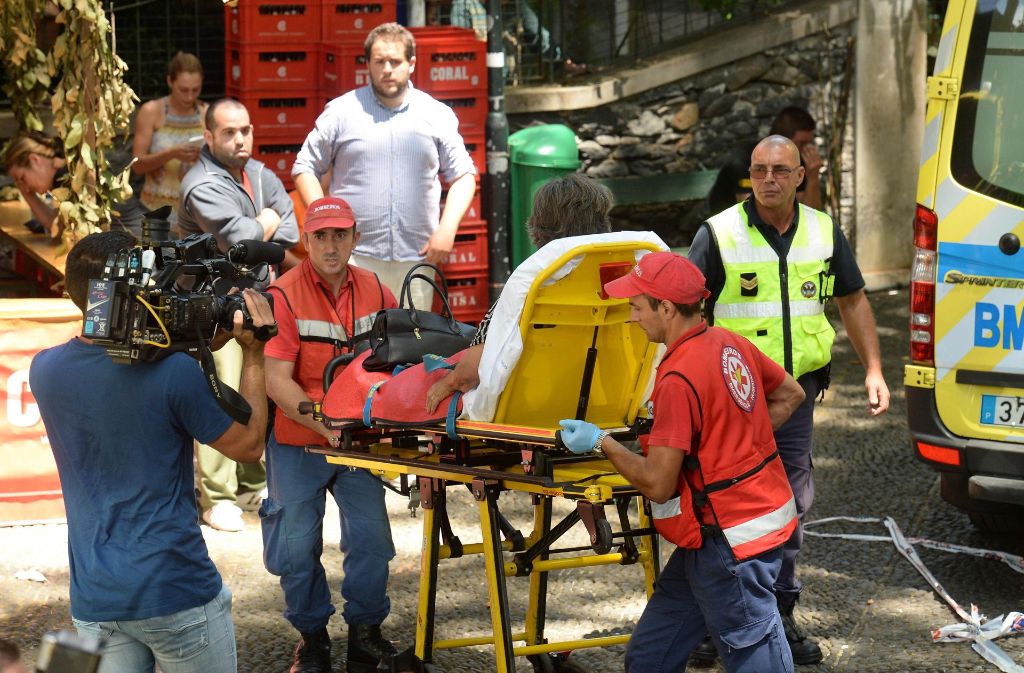 Nach dem Unglück auf Madeira transportieren Einsatzkräfte eine verletzte Person zu einem Rettungswagen. Ein umstürzender Baum begrub am Dienstag mehrere Menschen unter sich.