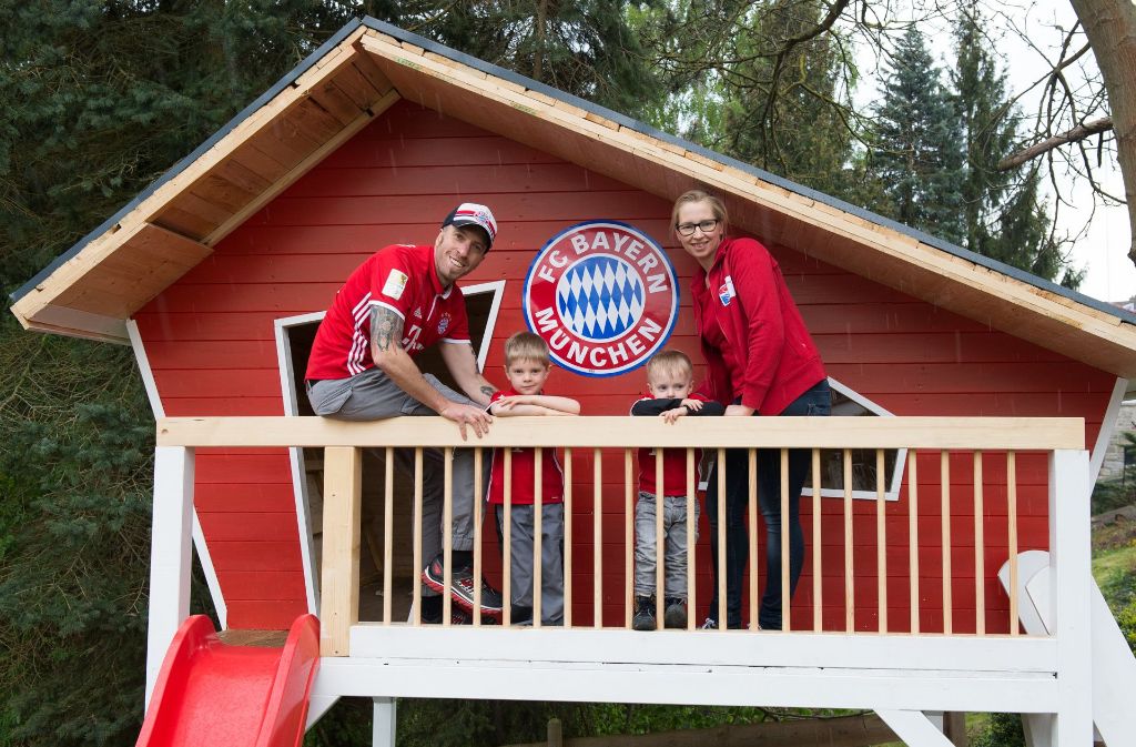 Der Fan des FC Bayern München, Bernhard Freitag, steht in Guxhagen (Hessen) an seinem Gartenhaus. Daneben stehen seine Frau Karin und die Kinder Jakob (rechts) und Jonathan. Der Fan hat auch sein Haus in den Vereinsfarben des Rekordmeisters gestrichen.