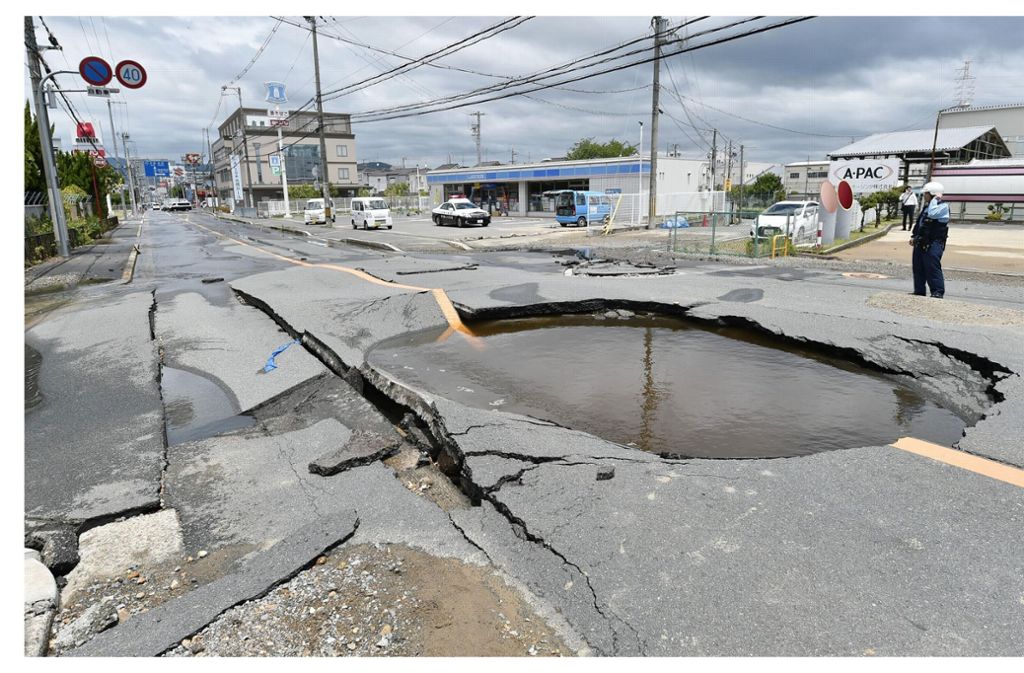 Ein mit Wasser gefüllter Krater auf einer Straße in Osaka, nachdem Wasserrohre nach einem Erdbeben gebrochen waren.