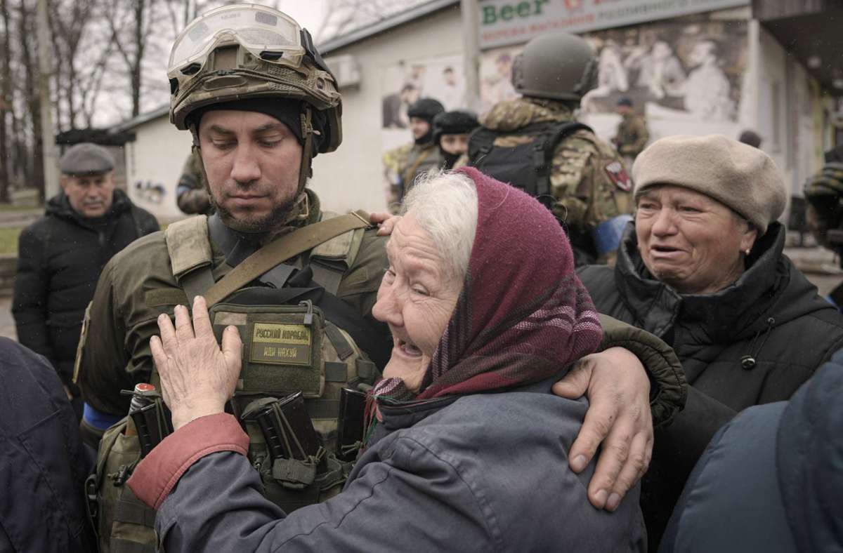 Eine Frau umarmt einen ukrainischen Soldaten, nachdem ein Konvoi von Militär- und Hilfsfahrzeugen in dem ehemals russisch besetzten Kiewer Vorort Butscha (Ukraine) eingetroffen ist.