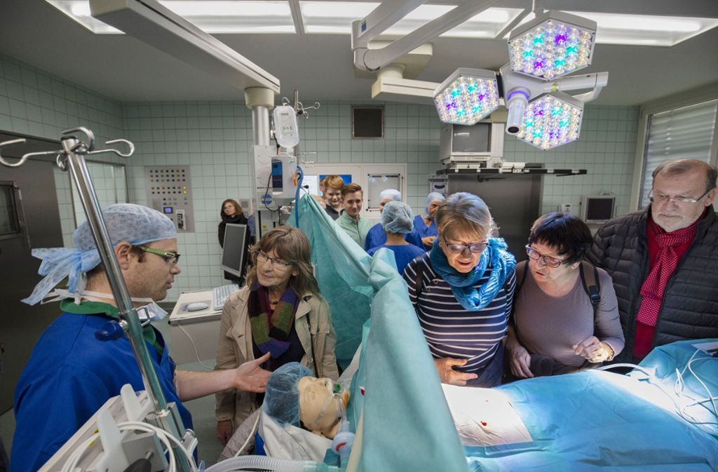 Der Notarzt Moritz Schmauk hat eine Besuchergruppe in seiner Obhut. Er erklärt, wie die Körperfunktionen eines Patienten während einer Operation überwacht werden.