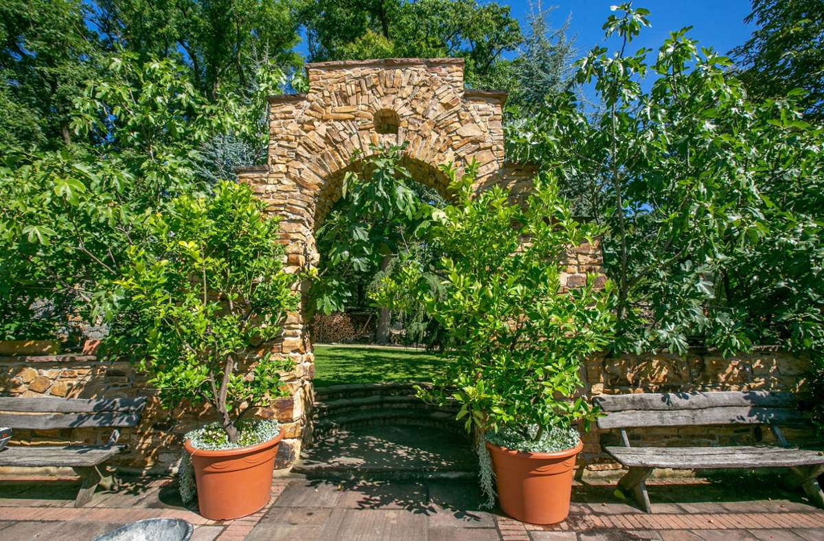 Ein antik anmutender Steinbogen verleiht dem Garten einen besonderen Charme.