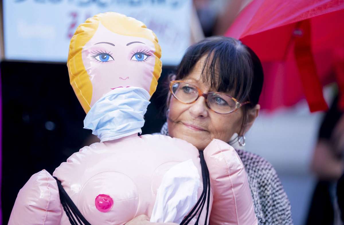Eine Teilnehmerin steht bei einer Protestaktion für die Öffnung von Prostitutionsstätten mit einer Sexpuppe im Arm nahe des Bundesrates. Foto: dpa/Christoph Soeder