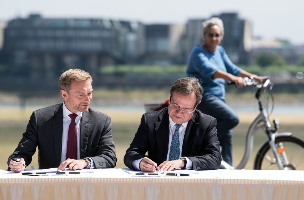 Politidylle: Christian Lindner (FDP/links) und Armin Laschet (CDU) unterzeichnen unter den Augen einer interessierten Bürgerin den Koalitionsvertrag. Foto: dpa