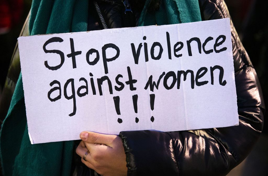 Eine Frau hält ein Schild mit der Aufschrift: „Stop violence against women!!!“