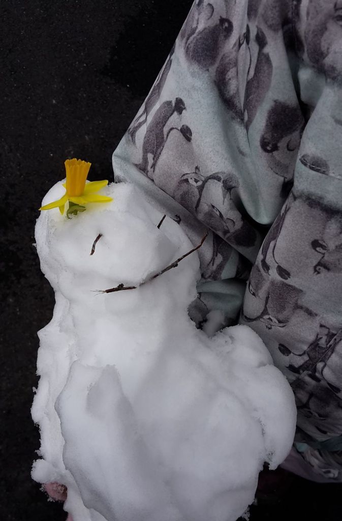 Ein kleiner Schneemann mit Krokus auf dem Kopf