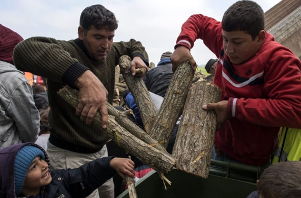 Flüchtlinge sammeln Brennholz, das von humanitären Organisationen in Idomeni angeliefert worden ist.