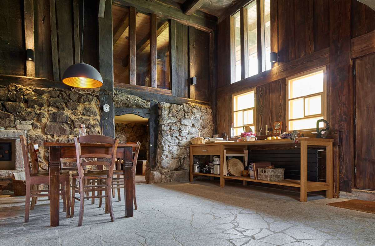 Blick in die Wohnküche mit Granitboden und viel Holz. Vertikale Glasfenster bringen Licht ins Heim.