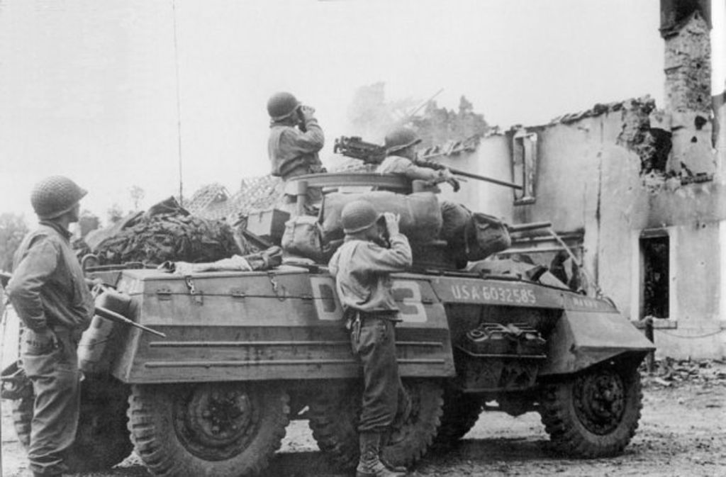 Ein amerikanischer Panzerwagen vor einem zerstörten Gebäude in der Normandie.